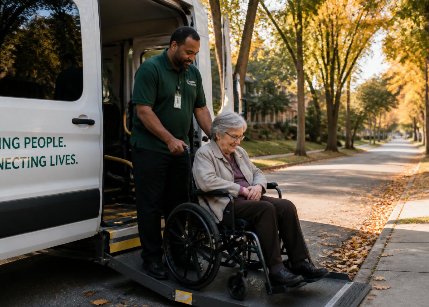 A driver assisting a rider in a wheelchair down a van ramp